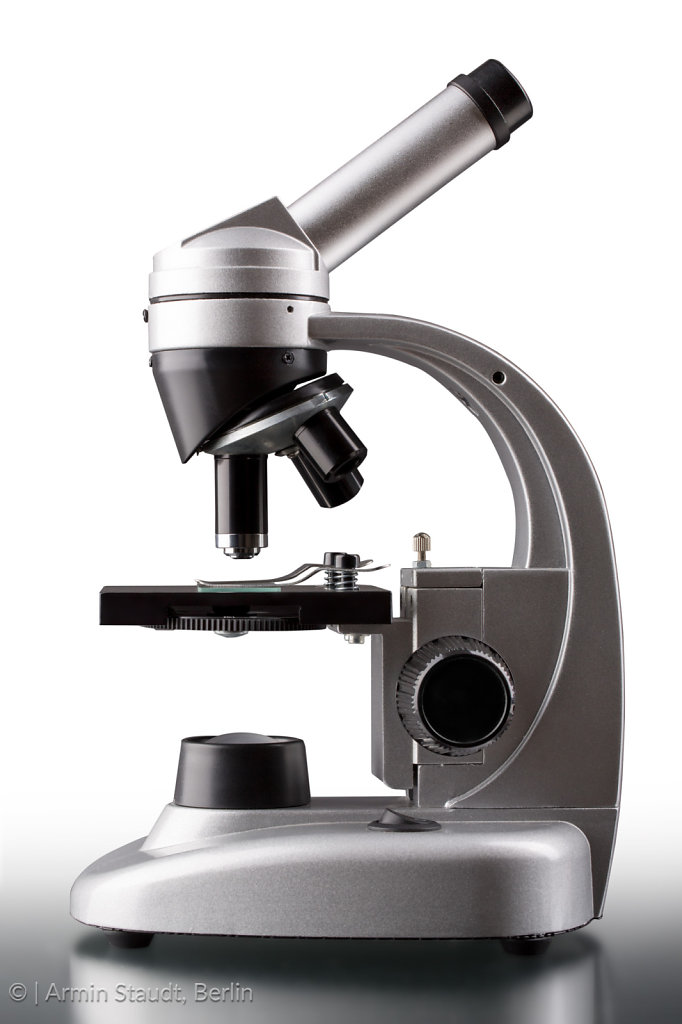 close up of a silver microscope, with white background