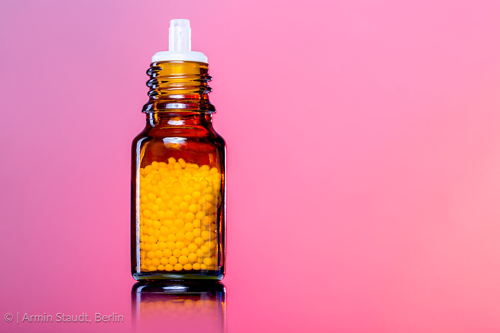 single bottles with homeopathy globules,white red background